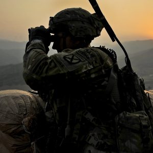 soldier on top of a mountain using binoculars